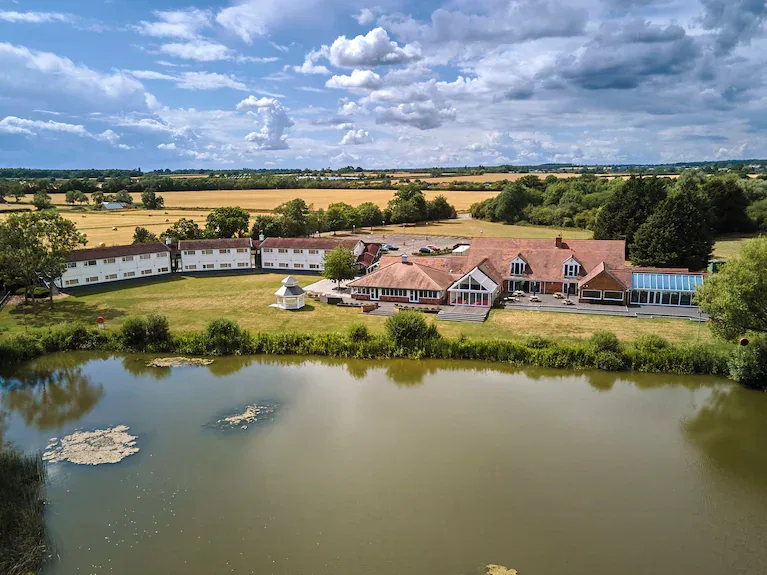 Aerial view of Lakehurst Park near Milton Keynes: the hotel and venue buildings beside the lake, surrounded by fields